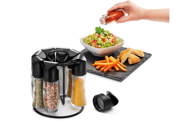 Draaibare plaat met kruiden, hand giet dressing over salade, frietjes op zwarte mat