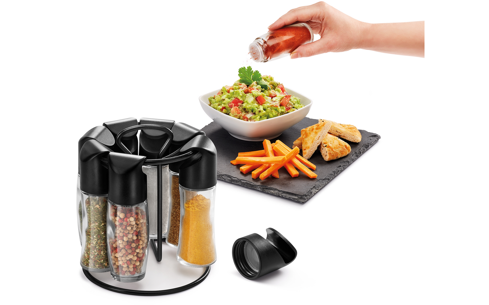 Draaibare plaat met kruiden, hand giet dressing over salade, frietjes op zwarte mat