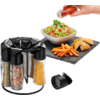 Draaibare plaat met kruiden, hand giet dressing over salade, frietjes op zwarte mat