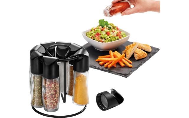 Draaibare plaat met kruiden, hand giet dressing over salade, frietjes op zwarte mat