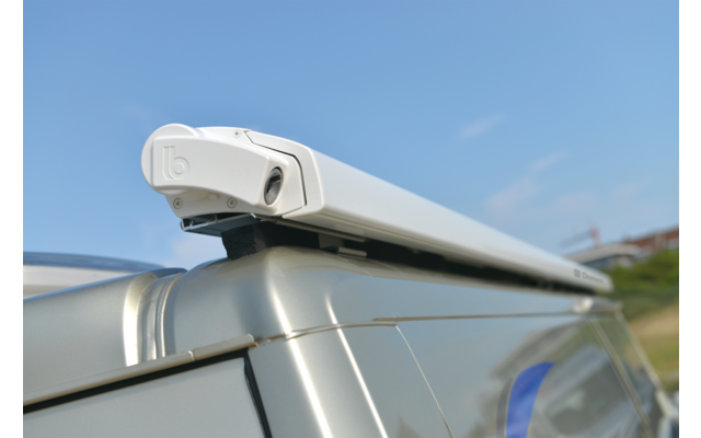 Boîtier blanc allongé sur le toit d'une camionnette argentée, ciel bleu en arrière-plan