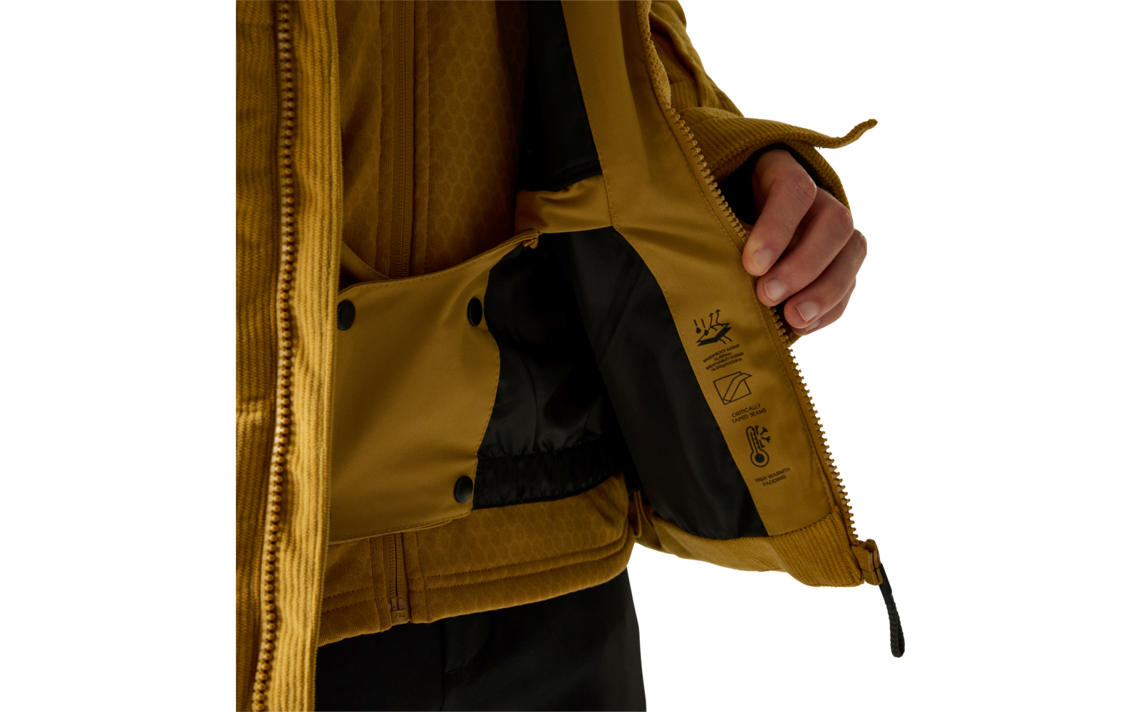 Hand öffnet senffarbene Jacke; schwarzes Innenfutter mit Pflegepiktogrammen, Reißverschluss, Druckknöpfe und Teil des Oberkörpers samt Hose sichtbar