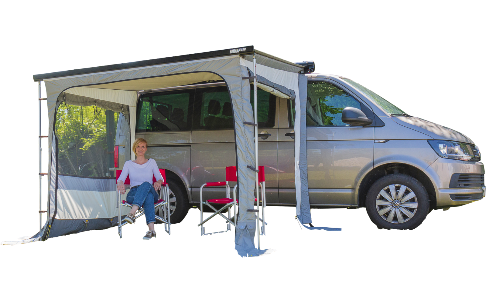 Hellgrauer Van mit ausgefahrener Markise; eine Person sitzt auf einem Klappstuhl neben einem kleinen roten Tisch, ein zweiter Klappstuhl daneben, die Seitentür des Fahrzeugs geöffnet