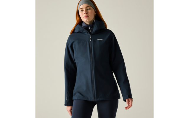 Person in dunkelblauer Jacke mit Reißverschluss und grauem Stirnband, frontal stehend, Hände seitlich, heller Hintergrund