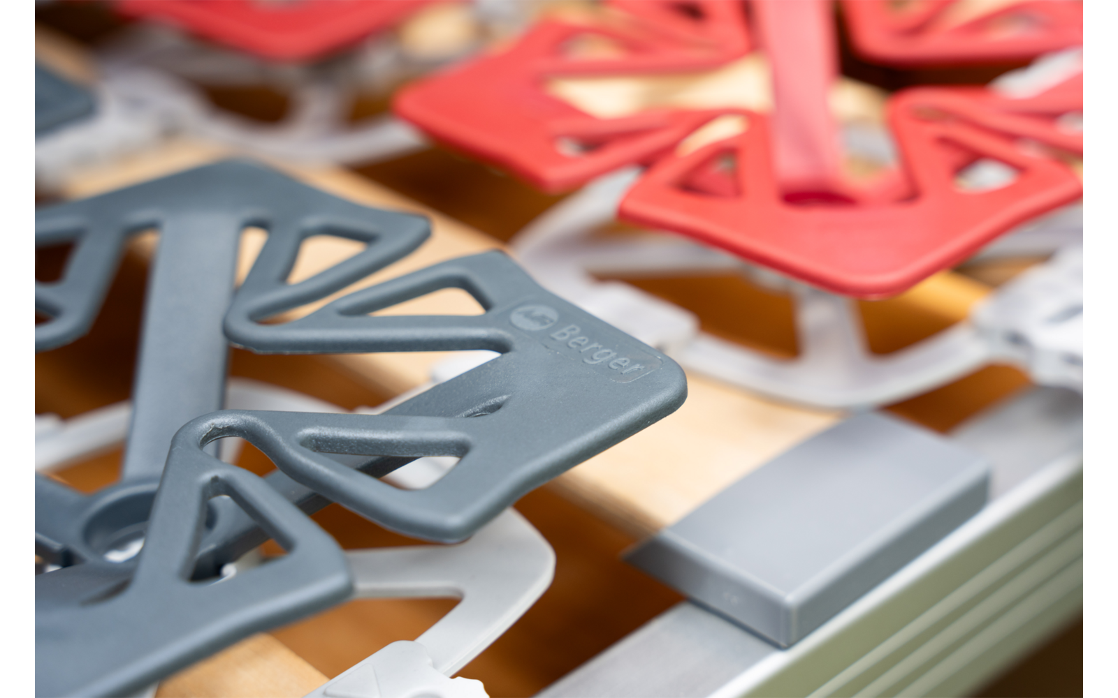 Close-up van meerdere rode en grijze kunststofelementen op een metalen frame met zichtbare houten latten