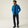 Mann mit blauer Jacke und dunkler Hose steht vor hellem Hintergrund