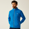 Mann mit kurzem Bart trägt eine blaue Jacke und schaut nach links