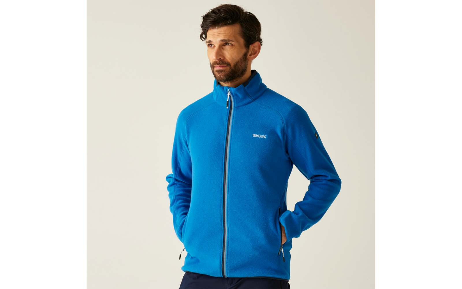 Mann mit kurzem Bart trägt eine blaue Jacke und schaut nach links