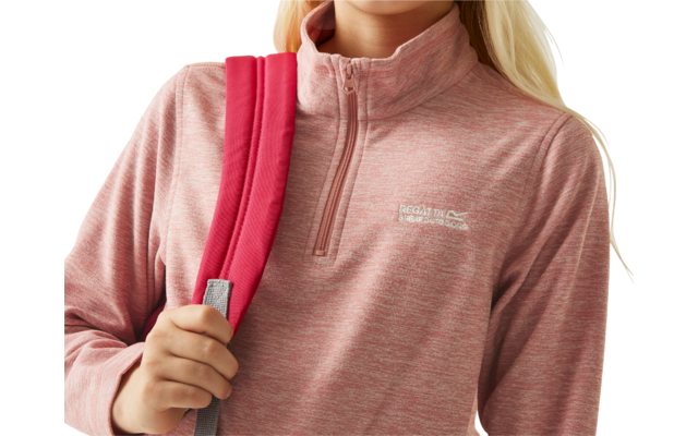 Vrouw met rode rugzak en roze trui kijkt naar rechts