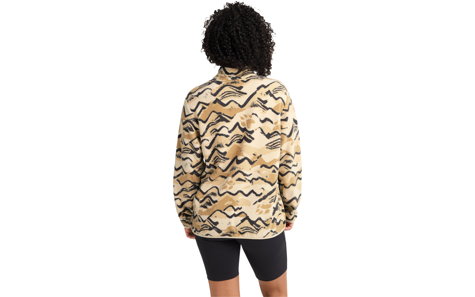 Person von hinten, lockiges dunkles Haar, beige Jacke mit schwarzem und braunem abstraktem Muster, schwarze Radlershorts