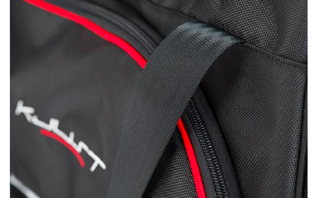 Nahaufnahme eines schwarzen Rucksacks mit roter Paspel, sichtbarem Reißverschluss und Tragegriff