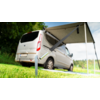 A gray van parked on grass with an extended awning