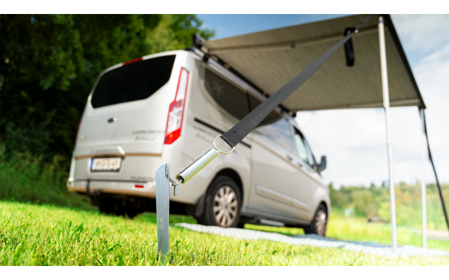 A gray van parked on grass with an extended awning