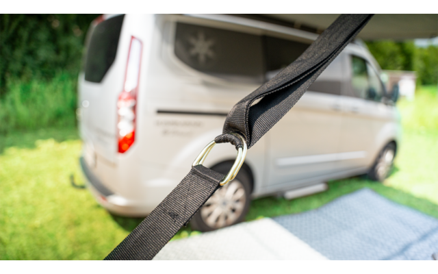 Close-up of a black seatbelt with a parked silver van in the background