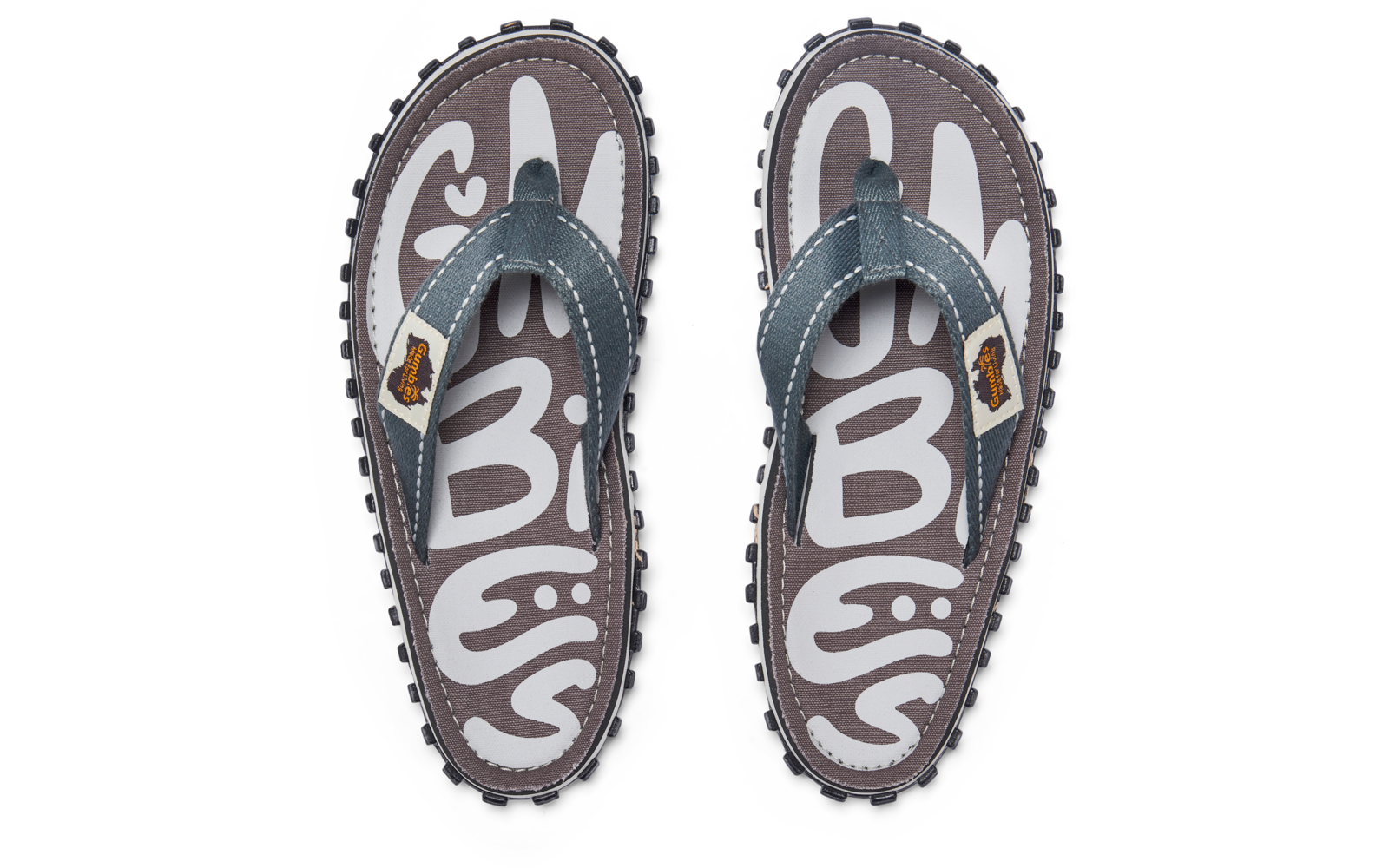 Top view of a pair of flip-flops with gray footbeds and white pattern, blue straps with white stitching and small brown logo patches