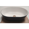 Oval basin with white interior and dark exterior, round wooden plug in drain, on wooden board, light background