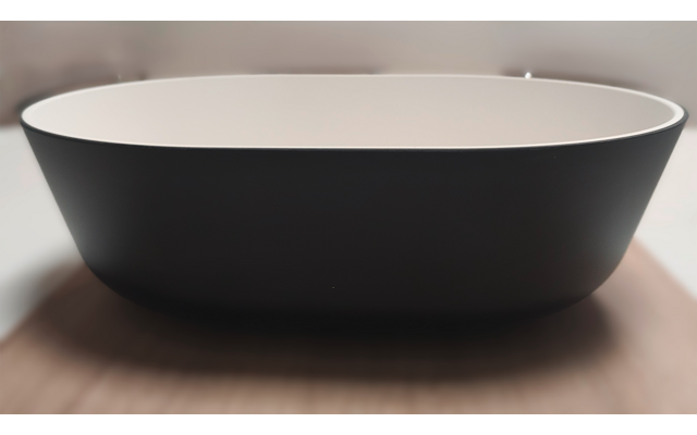 Black oval bowl with white interior on a wooden surface, blurred background