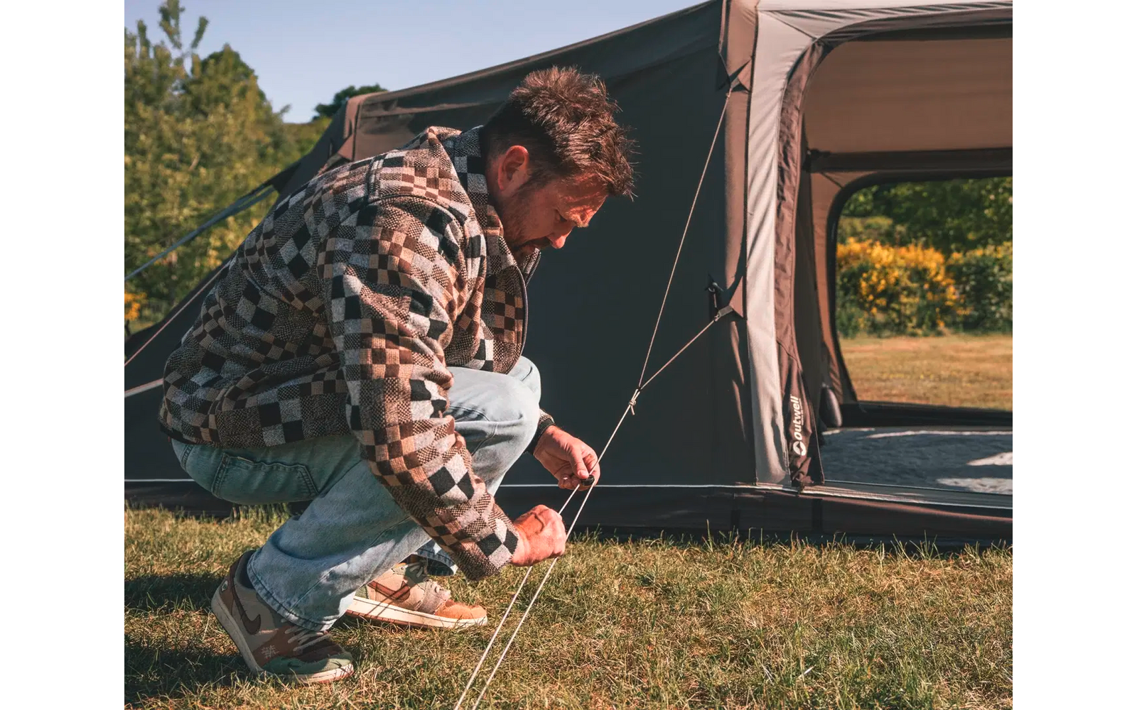 Mann kniet vor einem Zelt beim Camping im Freien
