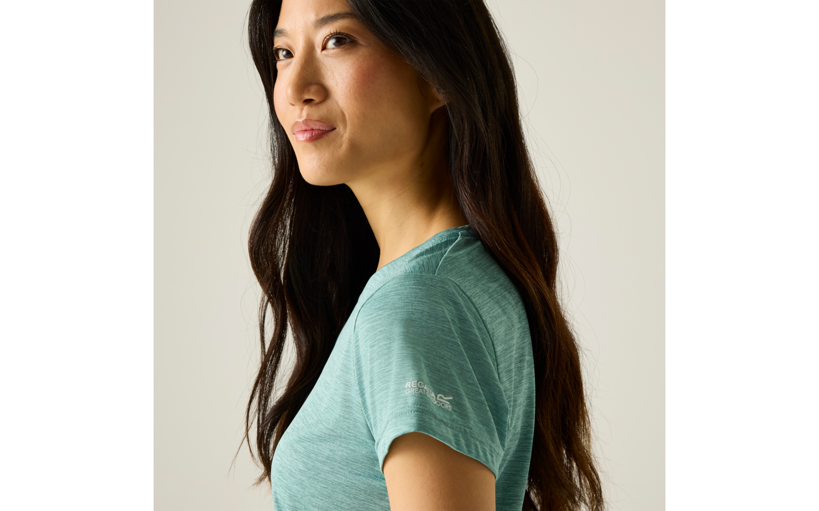 Zijaanzicht portret van een persoon met lang donker haar in een groen T-shirt tegen een lichte achtergrond