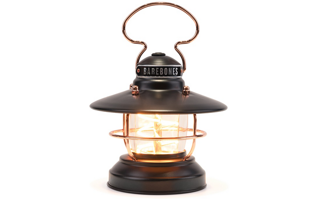 Zwarte metalen lantaarn met koperkleurige accenten, glascilinder met zichtbare filamentlamp, beschermend draadrooster en ronde handgreep bovenaan, BAREBONES op de bovenste ring