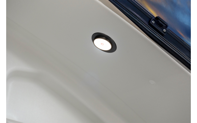 Revêtement intérieur d'un hayon avec un éclairage rond encastré, une petite empreinte circulaire et une partie de la lunette arrière avec reflet