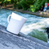White cup on a stone edge with water and blurred background