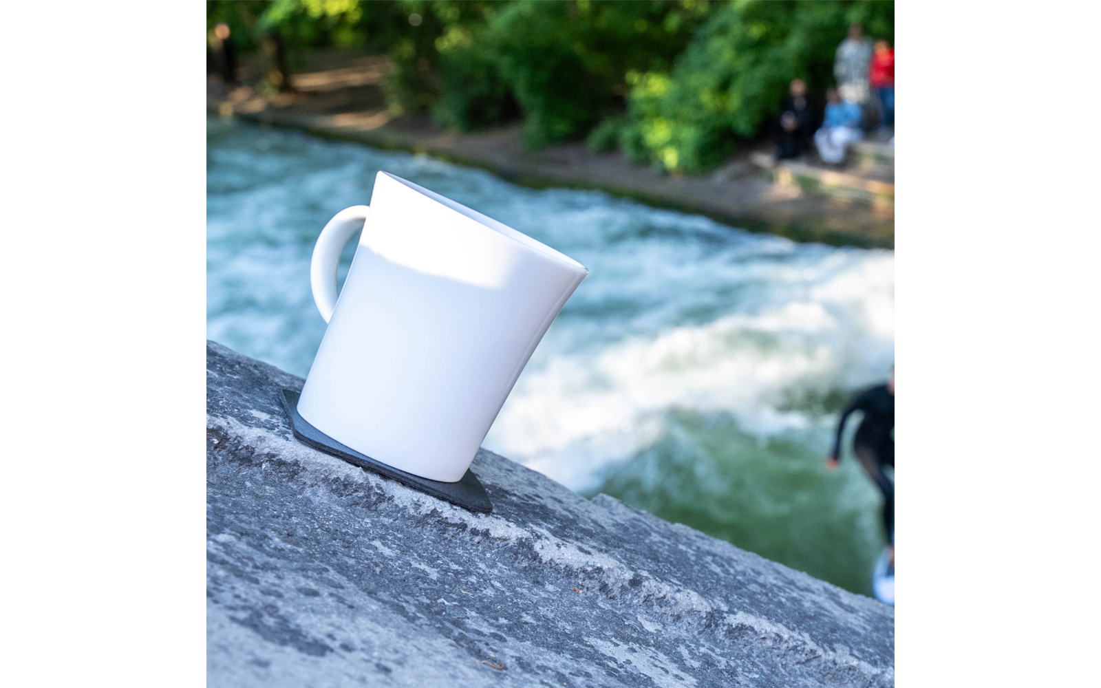White cup on a stone edge with water and blurred background