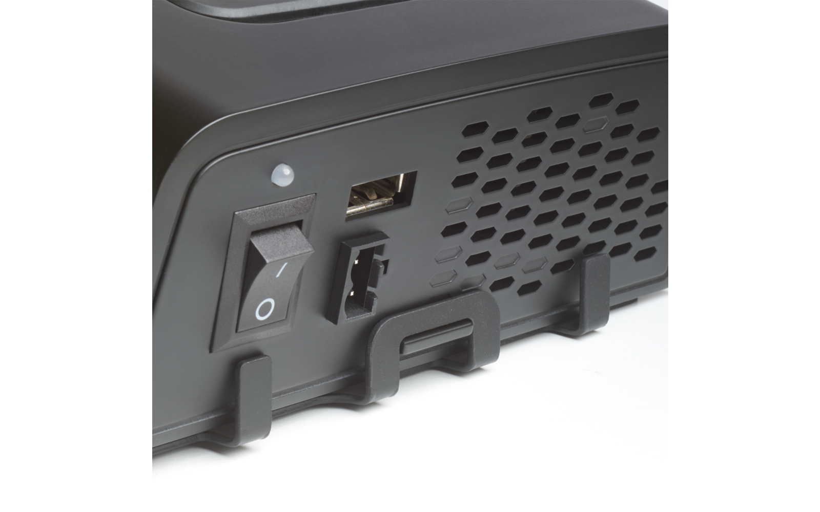 Nahaufnahme der Rückseite eines schwarzen Geräts mit Kippschalter (I/O), kleiner runder Leuchte, USB-A-Anschluss, rechteckigem Anschluss, wabenförmigem Belüftungsgitter und zwei Kunststoffhaltern