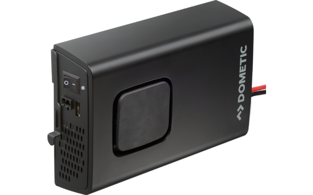 Schwarzes, rechteckiges elektronisches Gerät mit abgerundeten Kanten; rechts der Schriftzug "Dometic"; links Ein-/Ausschalter, Anschlussbuchsen und Lüftungsöffnungen; mittig ein quadratisches, leicht vertieftes Feld; rechts führen rote und schwarze K