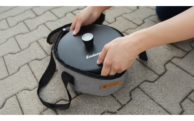 Des mains soulèvent un conteneur isolé gris avec un couvercle noir et un thermomètre sur un trottoir