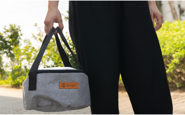 Personne tenant un sac isotherme gris avec poignées noires et étiquette en cuir