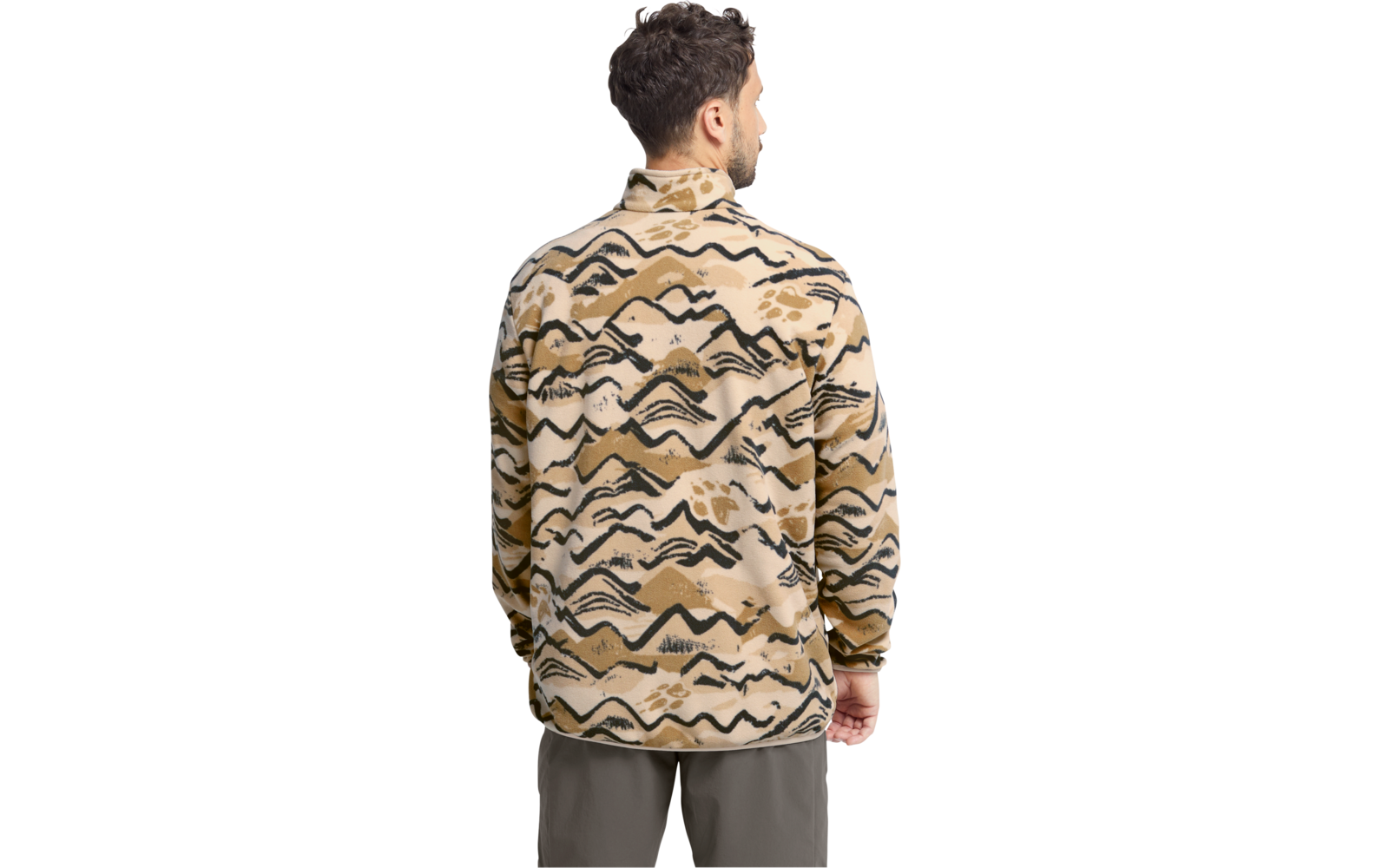 Person von hinten, trägt beige Jacke mit schwarzen geschwungenen und gezackten Mustern, hoher Kragen, lange Ärmel; olivgrüne Hose; kurzes dunkles lockiges Haar