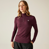 Femme aux longs cheveux bouclés porte un haut à manches longues violet foncé avec fermeture éclair et un pantalon noir sur fond neutre