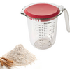 Transparante maatkan met rood deksel en handvat, schaalverdeling en etiket; daarnaast een hoop wit meel en twee tarwehalmen