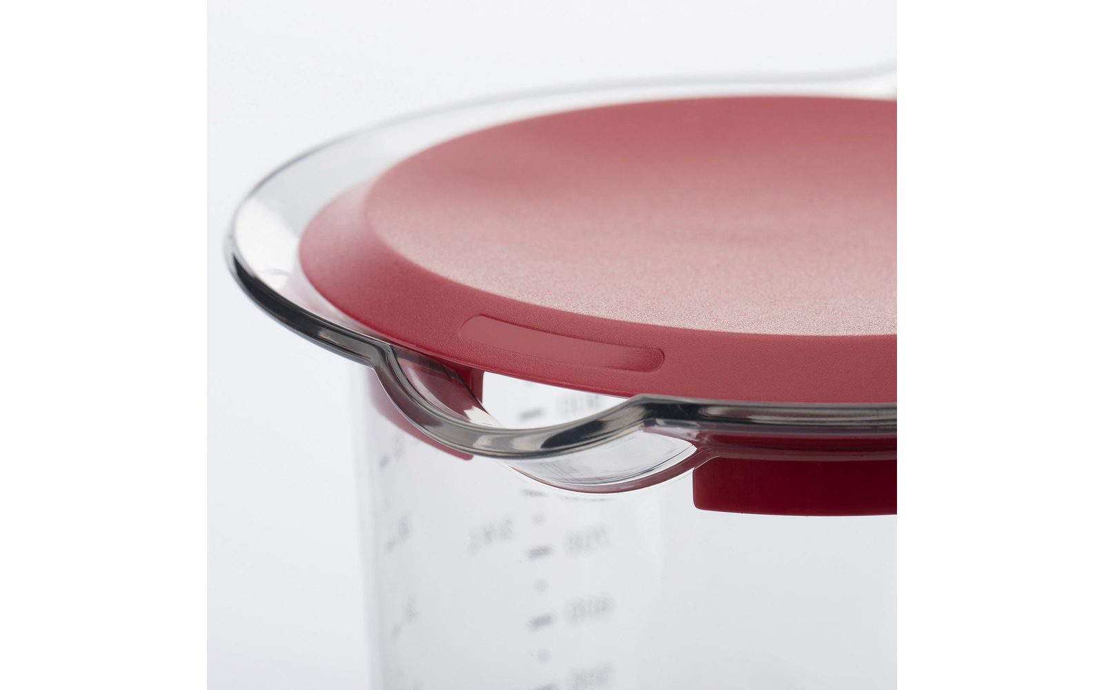 Close-up van een transparante maatbeker met zichtbare schaalverdeling en rode deksel met doorzichtige handgreep
