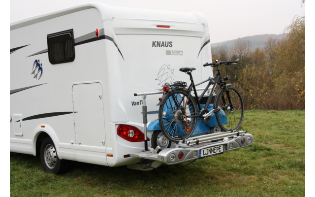 Weißes Wohnmobil steht auf grünem Feld, hinten zwei Fahrräder auf Fahrradträger montiert