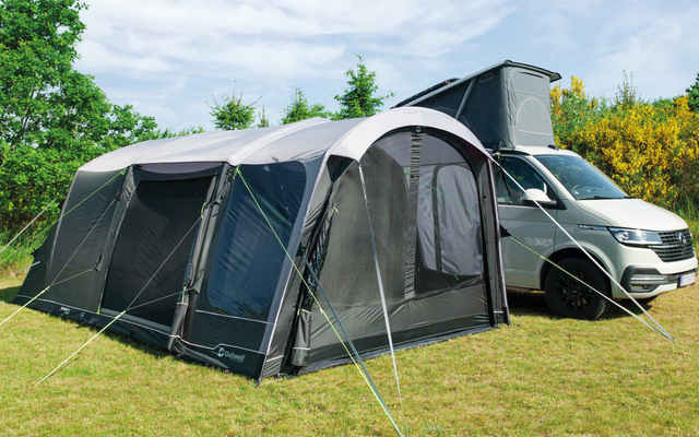 Tent with attached awning next to a white car on a grassy field