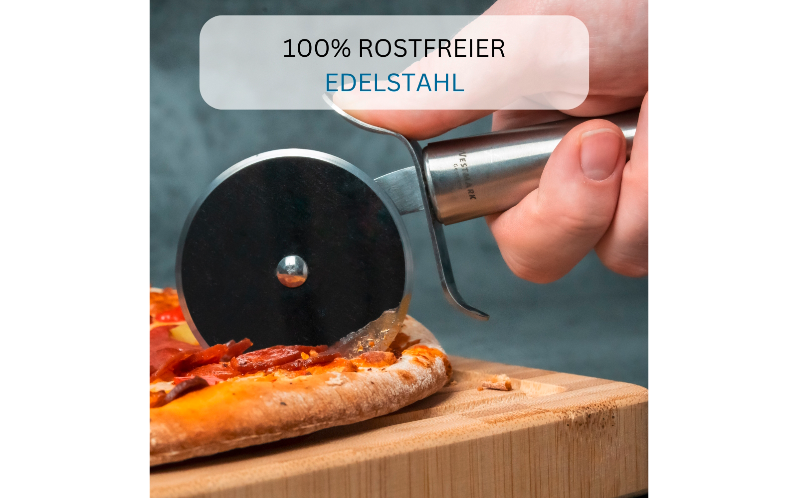 Hand hält einen Pizzaschneider mit runder Klinge, schneidet eine Pizza mit geschmolzenem Käse und roten Scheiben auf einem Holzbrett; oben ein Banner mit dem Text 100% ROSTFREIER EDELSTAHL