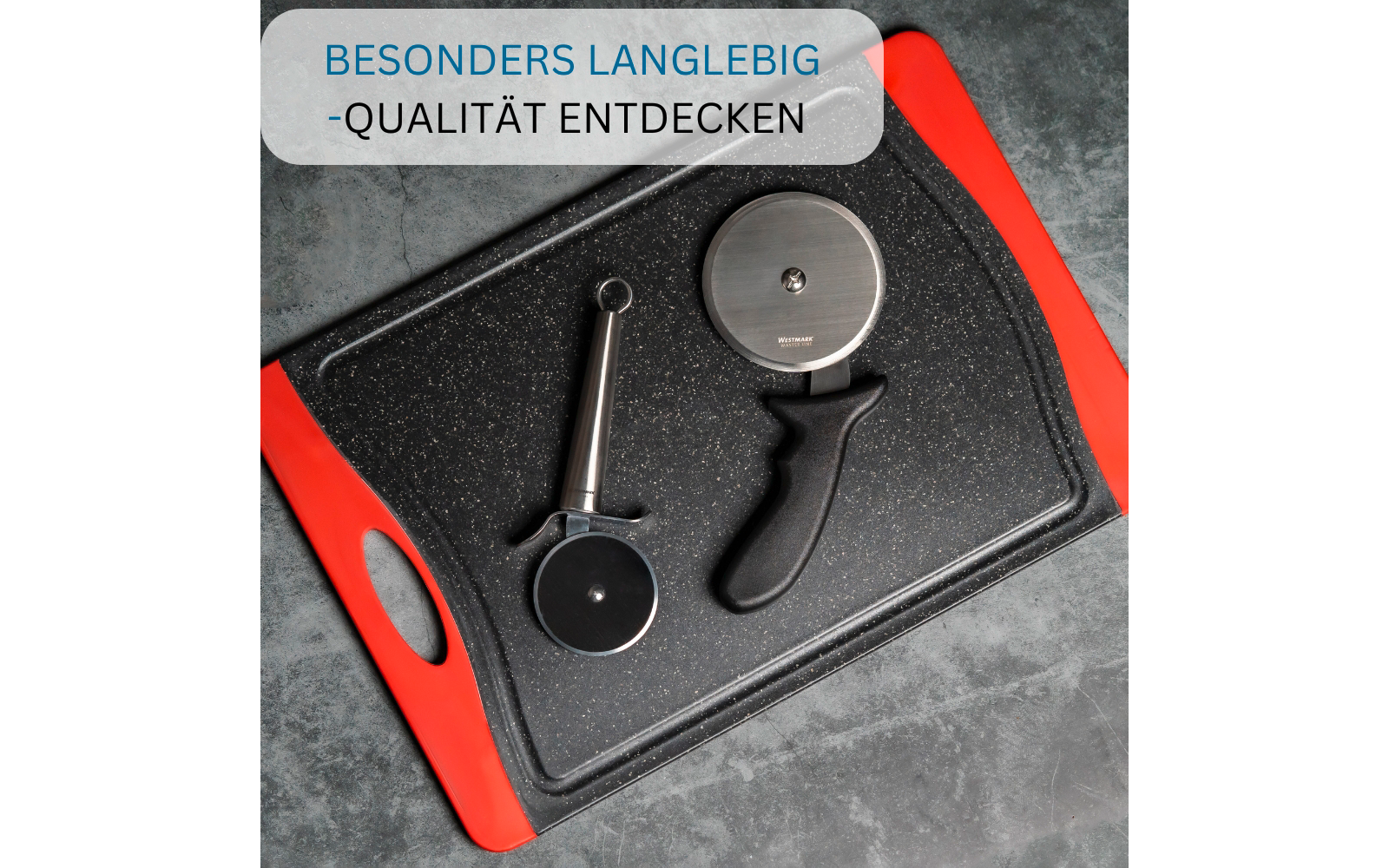 Schwarzes, körniges Schneidebrett mit roten Griffen auf grauem Untergrund; darauf zwei Pizzaschneider (einer mit langem Metallgriff, einer mit schwarzem Kunststoffgriff); oben links halbtransparenter Textbanner „BESONDERS LANGLEBIG - QUALITÄT ENTDECK