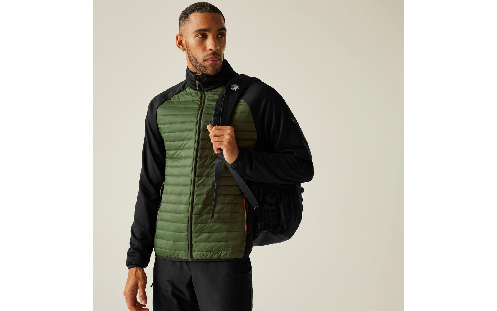 Mann trägt grüne gesteppte Jacke und schwarzen Rucksack