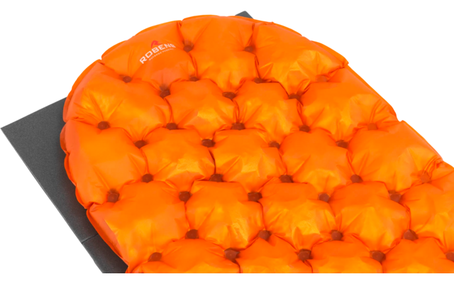 Een vierkant zitkussen met oranje gestoffeerde knopen op een zwarte ondergrond