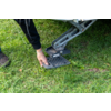 Hand setzt ein quadratisches Kunststoffgitter unter eine Metallstütze eines Fahrzeugs auf Gras