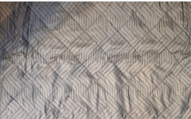 Superficie in tessuto grigio chiaro con linee diagonali scure a zigzag e pieghe