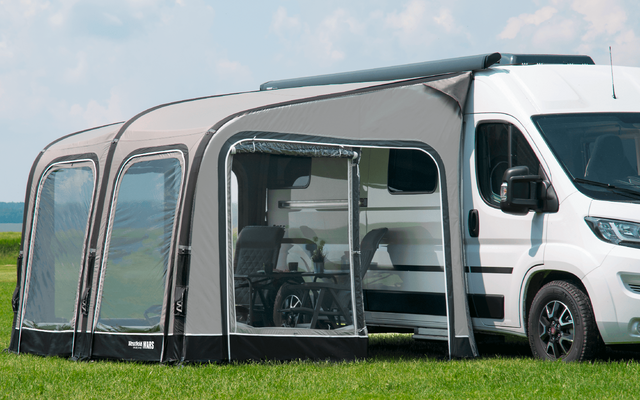 Motorhome with attached gray awning on a green lawn
