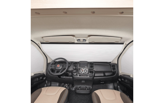 Interno anteriore di veicolo con tendine plissettate chiuse su parabrezza e finestrini laterali; volante a sinistra, cruscotto centrale con display e comandi, due sedili anteriori beige, rivestimento del soffitto chiaro con luci