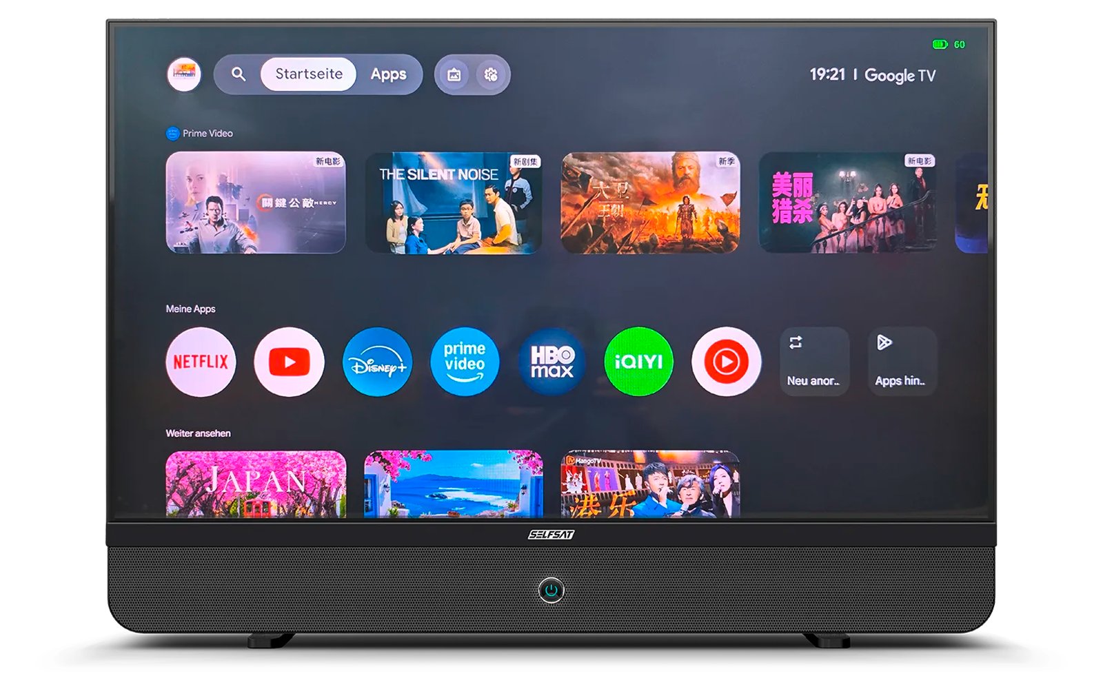Televisore nero che mostra la schermata principale Google TV con ora 19:21, barra di ricerca, miniature di anteprima e icone delle app (Netflix, YouTube, Disney+, Prime Video, HBO Max, iQIYI). Piccola LED blu sulla cornice inferiore