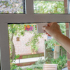 Hand öffnet ein Fenster bei Tageslicht, im Hintergrund unscharfer Garten zu sehen