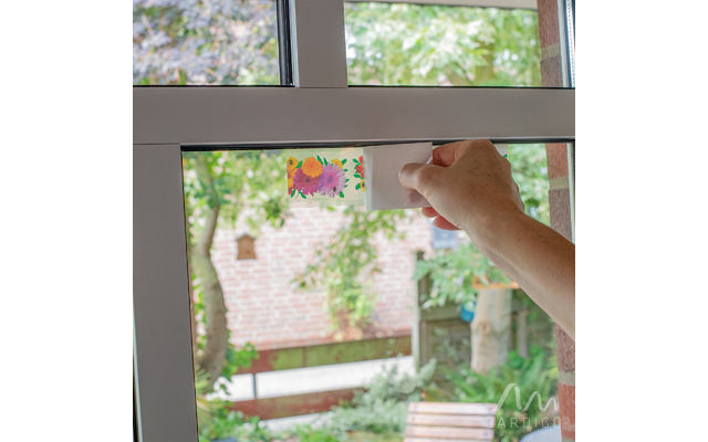 Hand öffnet ein Fenster bei Tageslicht, im Hintergrund unscharfer Garten zu sehen