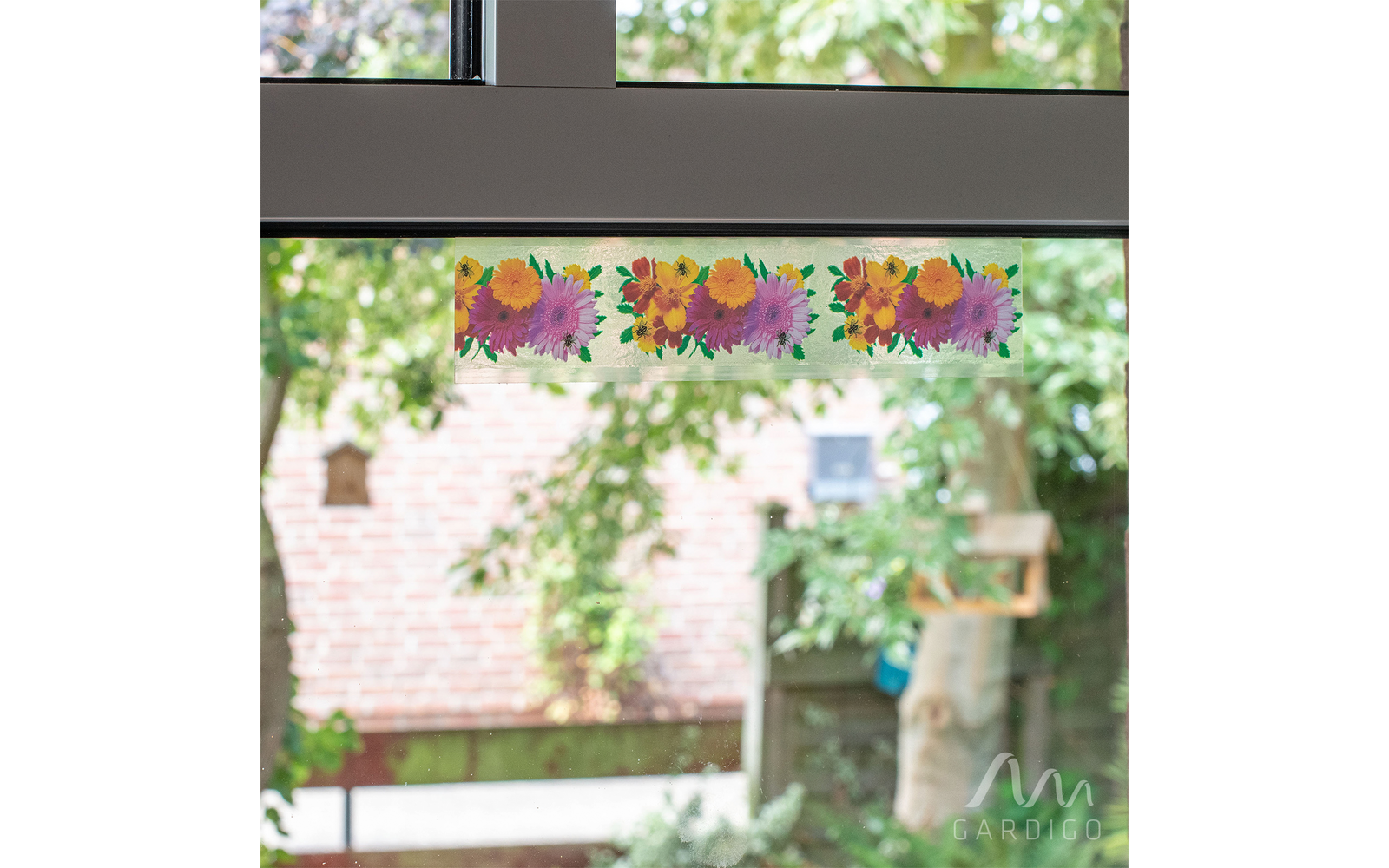 Bunte Papierblumen hängen an einer Fensterscheibe