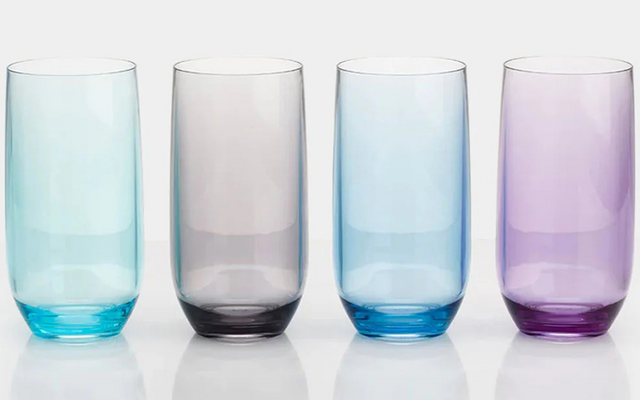 Cuatro vasos altos uno al lado del otro sobre fondo blanco, colores de izquierda a derecha: azul claro, gris, azul claro, morado; reflejos abajo